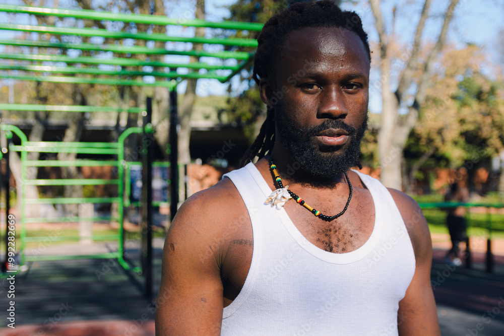 Portrait of a serious African sports man with dreadlocks in the park sweating looking at the camera Portrait of a serious African sports man with dreadlocks in the park sweating looking at the camera