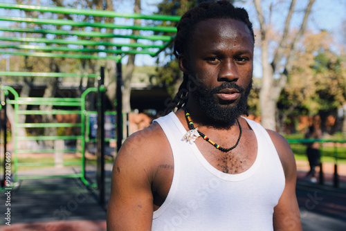 Portrait of a serious African sports man with dreadlocks in the park sweating looking at the camera