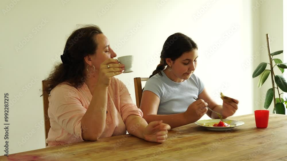 Mother and daughter have breakfast at the table