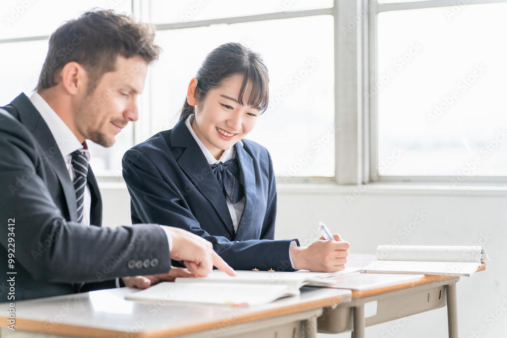 教科書を指差して教える欧米人講師と勉強する高校生・中学生
教科書を指差して教える欧米人講師と勉強する高校生・中学生