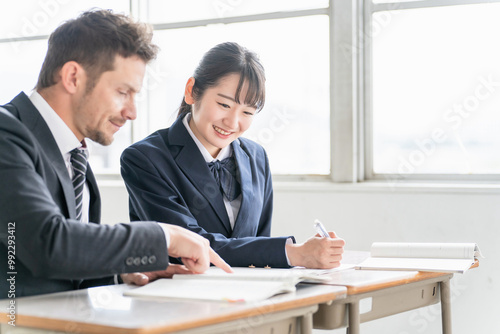 教科書を指差して教える欧米人講師と勉強する高校生・中学生 