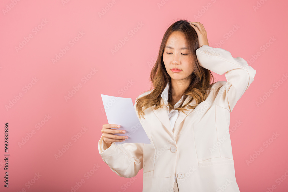 Portrait of beautiful Asian young woman sad tired strain holding paper calculating bills on hand, female person problem she hold worried over bill, studio shot isolated on pink background Portrait of beautiful Asian young woman sad tired strain holding paper calculating bills on hand, female person problem she hold worried over bill, studio shot isolated on pink background