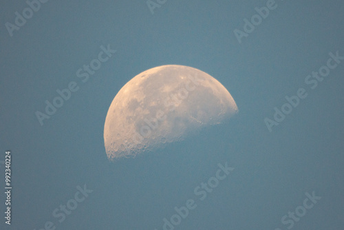 A partial moon hangs in the daylight sky