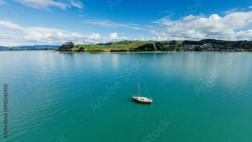 Lone sailing boat moored in calm waters in Maraetai, Auckland, New Zealand. photo