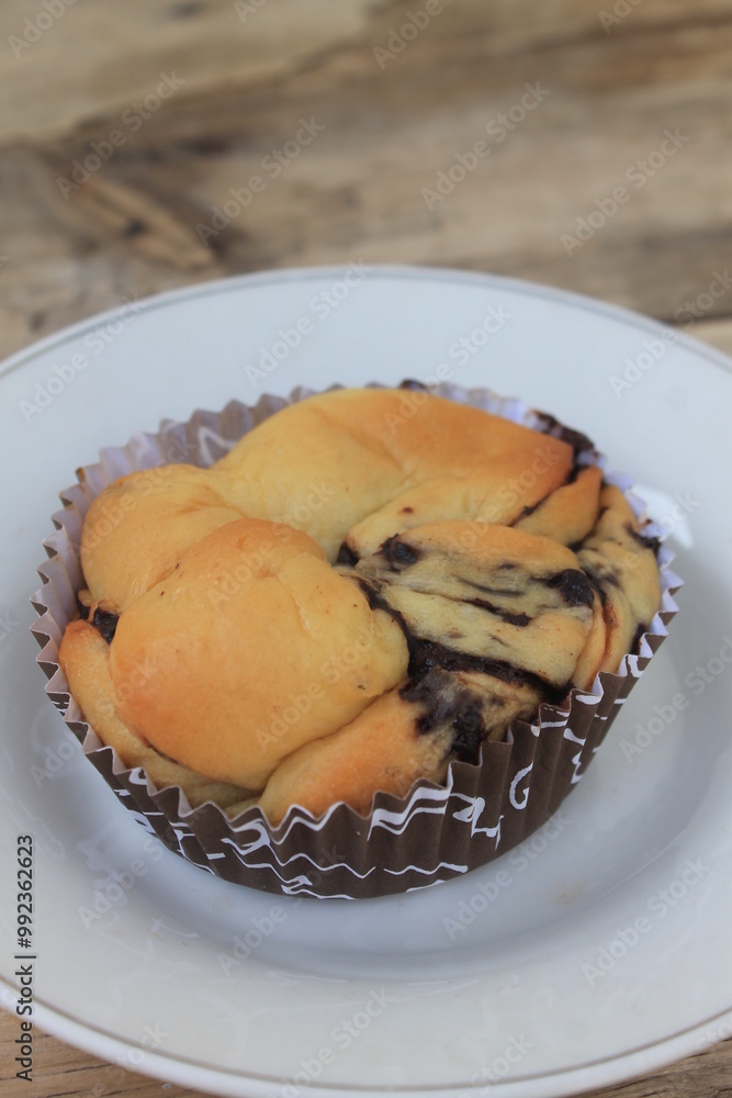 Chocolate filled bread in a paper cup in a plate on the table


