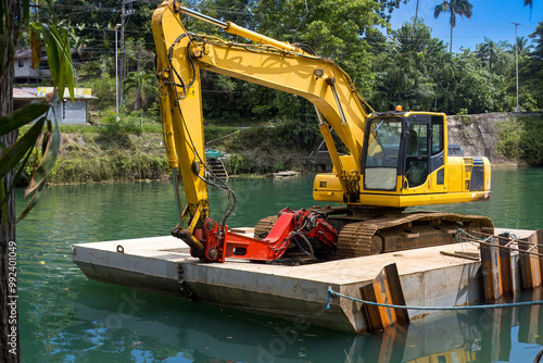 Excavator on a floating platform, cleaning and deepening the river photo