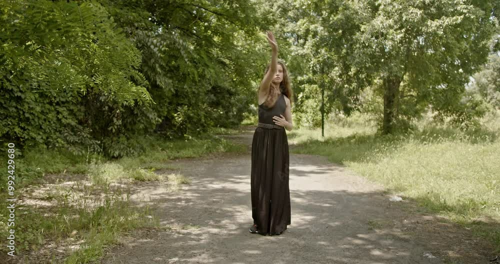 A young woman gracefully dances contemporary dance in a peaceful forest setting. A young woman gracefully dances contemporary dance in a peaceful forest setting.