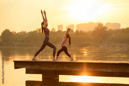 Mom And Daughter Doing Yoga In A Park
