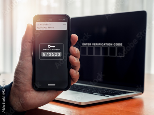 2FA or two factor authentication, cyber security concept. Passcode number key, sms showing on smart mobile phone screen in hand while waiting verification code for login website by laptop computer.