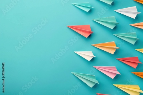 Colorful paper airplanes flying on a turquoise background, representing creativity, innovation, and adventure The vibrant shades of pink, orange, white, green, and blue create an engaging visual con