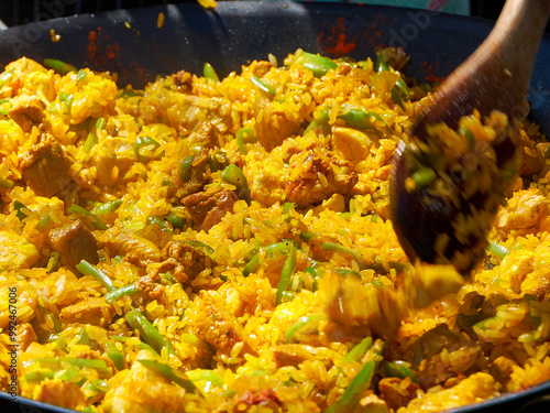 Close up while cooking a paella with vegetables, pork and seafood outdoors