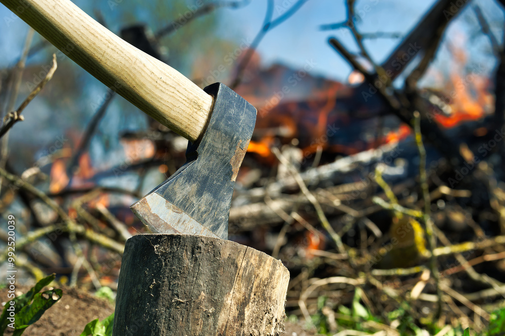 Axe stuck in a log against burning campfire Axe stuck in a log against burning campfire