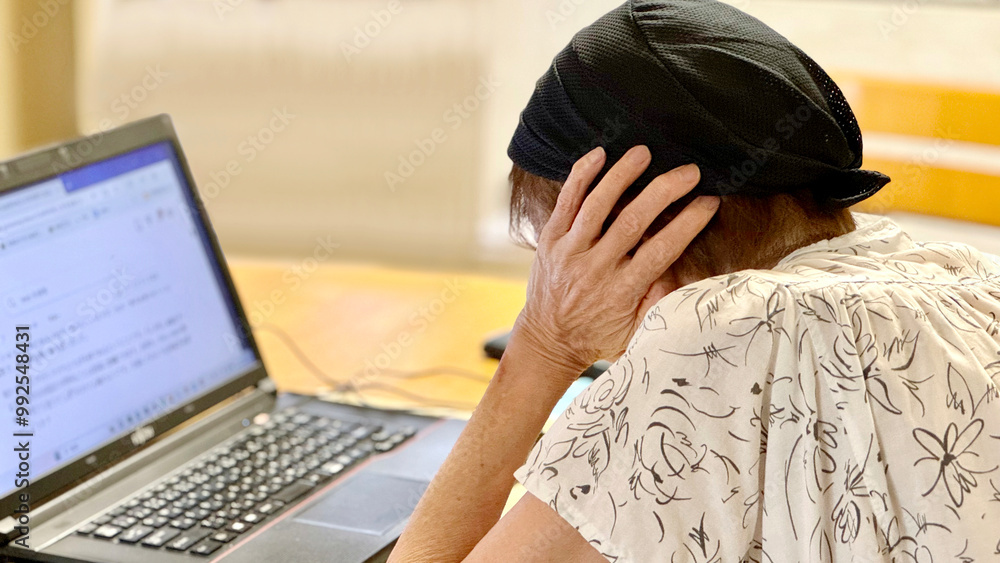 Naklejka premium ノートパソコンの前で耳をふさぐ高齢女性_左から