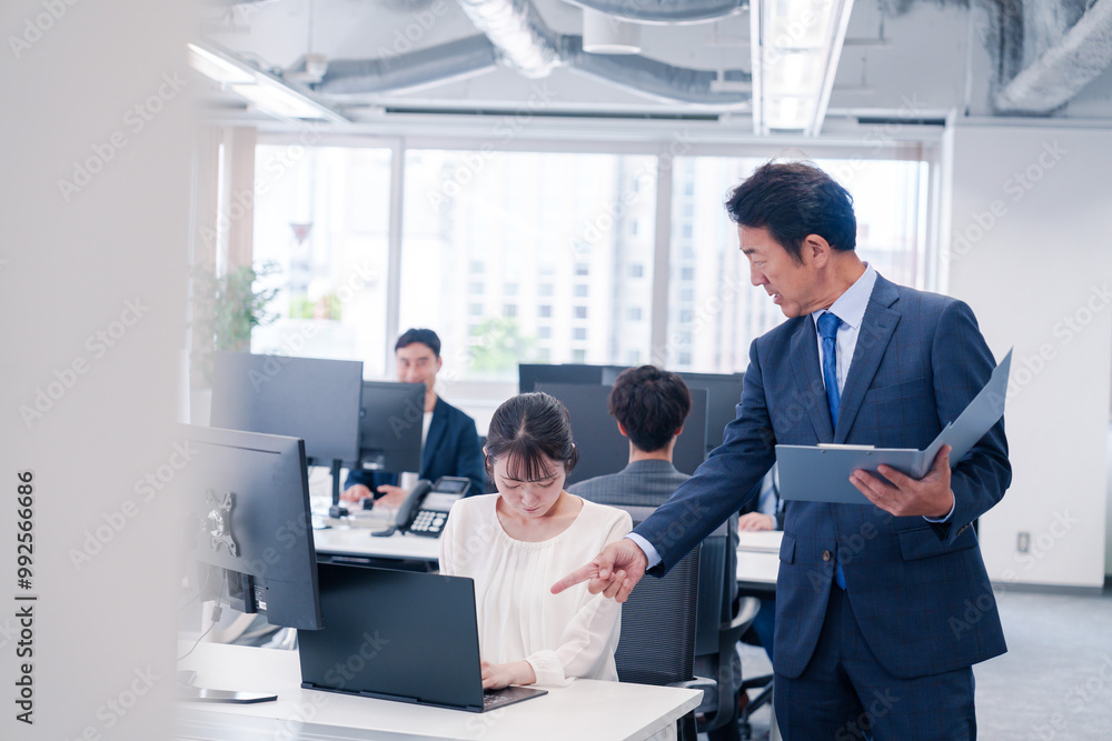 オフィスで上司から叱責をされる若い女性社員 オフィスで上司から叱責をされる若い女性社員
