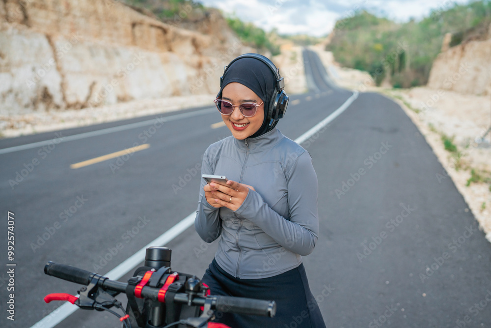 hijab biker using phone when riding bike, biking concept hijab biker using phone when riding bike, biking concept