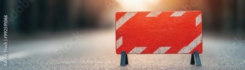 A bright orange roadblock stands on an empty street, signaling construction or detour ahead at sunset. Caution is advised.