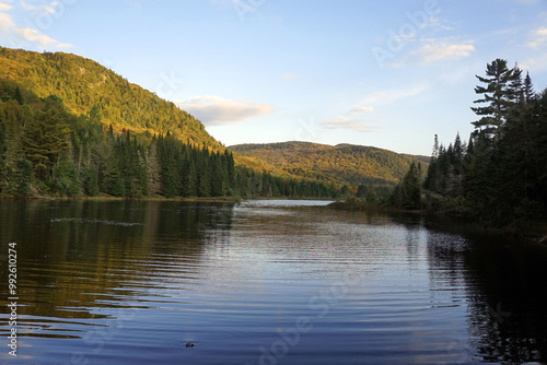 Lake surrounded by forested hills in the early evening