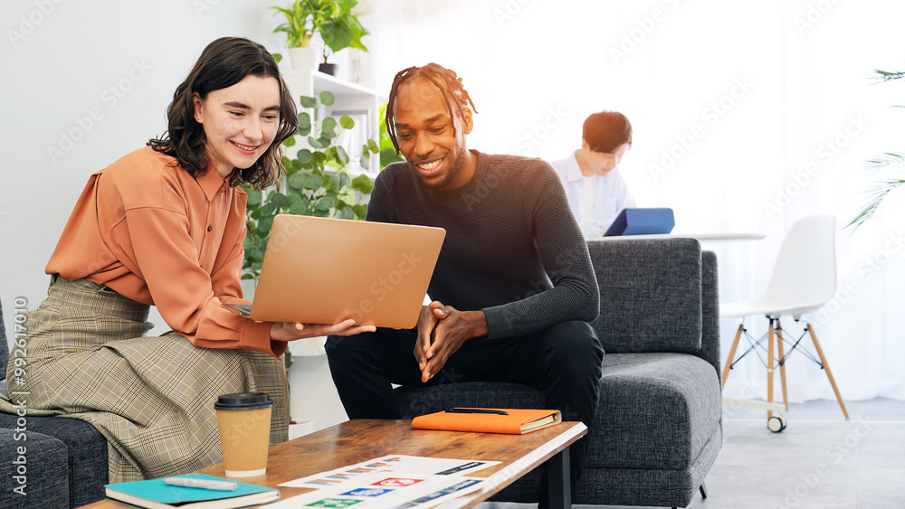 Multinational people talking while looking at a laptop in a lobby Multinational people talking while looking at a laptop in a lobby