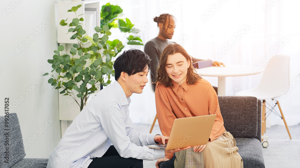 Multinational people talking while looking at a laptop in a lobby Multinational people talking while looking at a laptop in a lobby