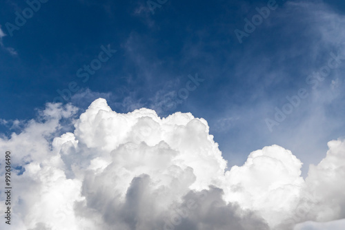 Cumulus clouds drift across the electric blue sky, creating a picturesque atmospheric phenomenon in the natural landscape. A beautiful meteorological event enhances the scenic view.