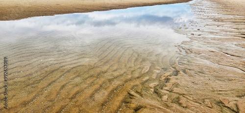 Reflection of cloudy sky on sea water with texture for wave on sand beach landscape. photo