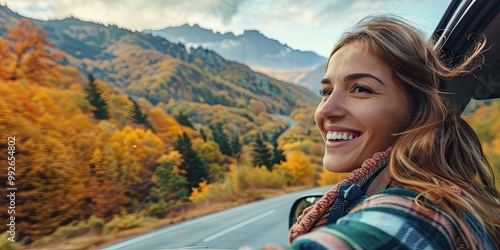 Woman with a beaming smile, sitting in her car with the windows down, taking in the stunning autumn scenery on a mountain road.