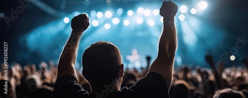 An enthusiastic concertgoer raises hands in excitement at a live music performance, capturing the thrill of the crowd. photo