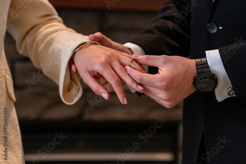 Male groom putting on a diamond wedding ring on a female bride. Wedding ceremony.