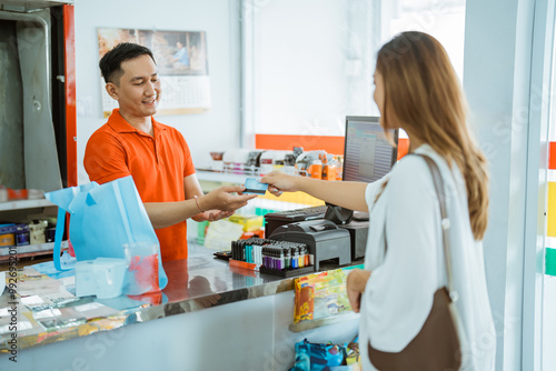 male store cashier serves non-cash payments by female buyers in minimarkets photo