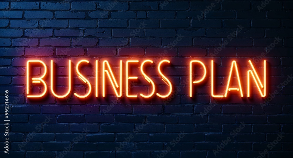 Obraz premium business plan word lettering glowing with neon light on dark brick wall background