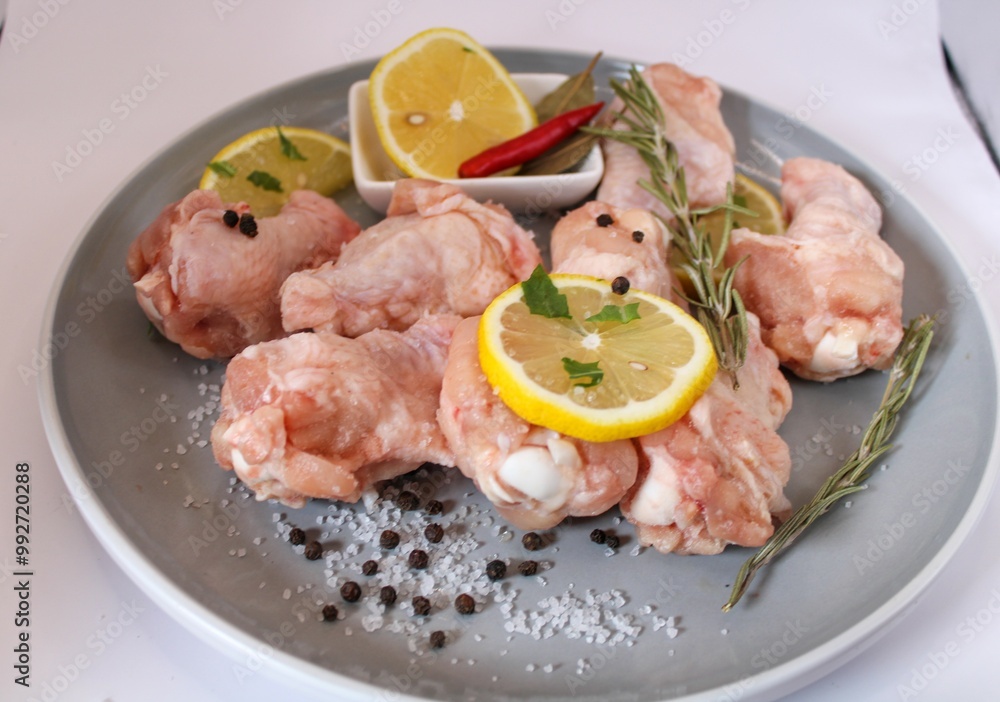 raw chicken wings with pepper and lemon on the plate raw chicken wings with pepper and lemon on the plate