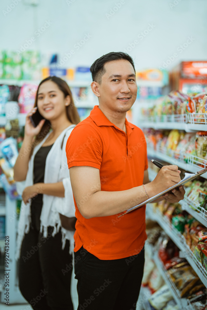 male worker smiles into camera while standing carrying clipboard in supermarket male worker smiles into camera while standing carrying clipboard in supermarket