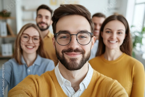 Young professionals taking a group selfie in a creative office space, casual attire, vibrant decor, startup culture, camaraderie concept