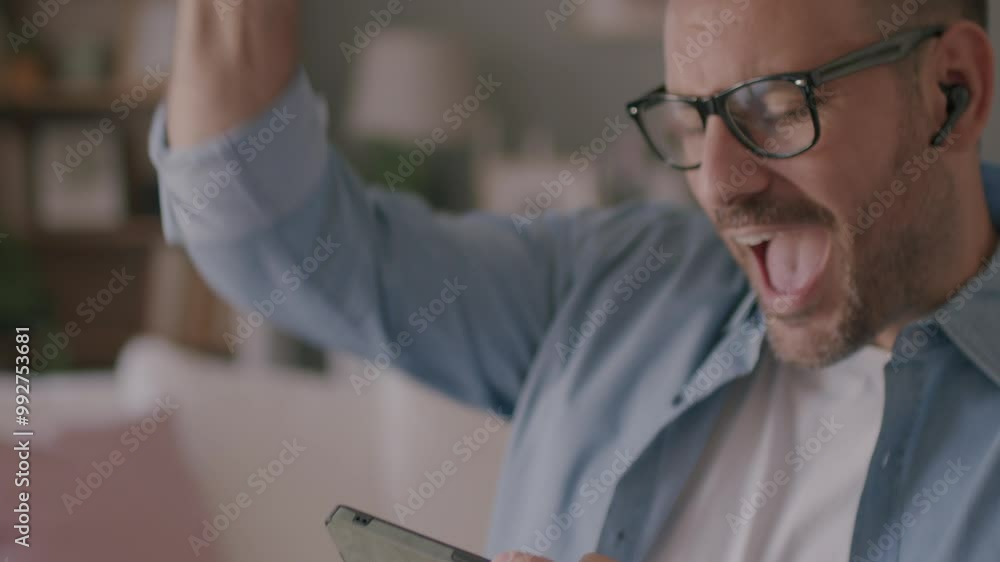 A Caucasian man sits at home play video games on a smartphone mobile phone and he is winning. 4k video A Caucasian man sits at home play video games on a smartphone mobile phone and he is winning. 4k video