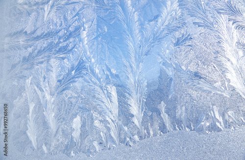 Frost patterns on frozen glass on a winter day. Winter frosty texture natural background