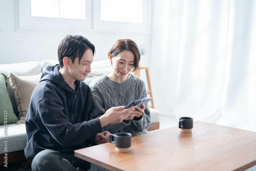 笑顔で携帯を見る日本人カップル 笑顔で携帯を見る日本人カップル