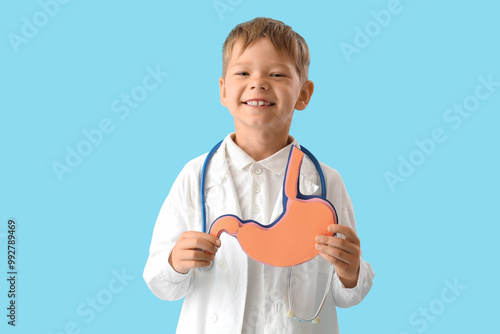 Little doctor with paper stomach on blue background photo