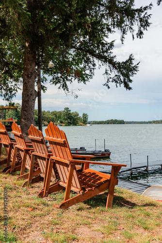 Canvas Print Adirondack chairs facing lake at shoreline