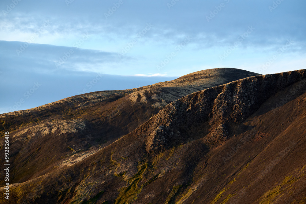 Fototapeta premium Rocky mountain formation with brown cliffs against cloudy blue sky