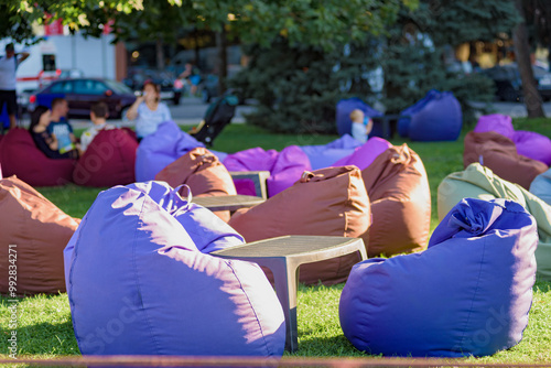 Many colorful bean bags chairs in park on green lawn. Soft chairs on the grass offer relaxation and rest, perfect for a weekend getaway in the city photo