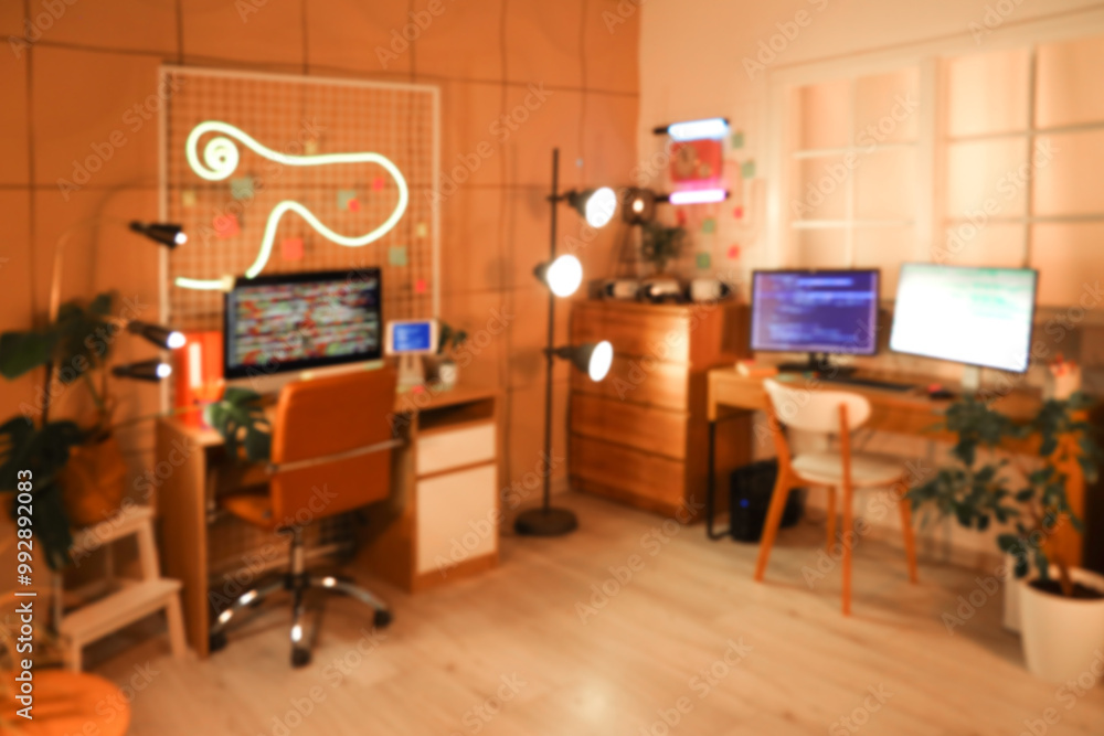 Fototapeta premium Blurred view of programmer's office with desks and glowing lamps at night