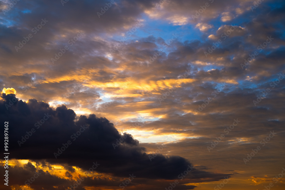 Dramatic sunset paints the sky with vibrant shades of orange, pink, and dark purple, silhouetting buildings below and creating a breathtaking evening scene full of depth and color.