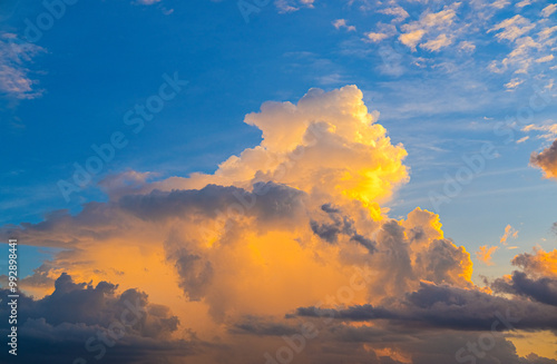 Obraz na płótnie Fluffy clouds glow with warm golden light against a vibrant blue sky, creating a stunning and peaceful scene that captures the beauty of nature’s ever-changing canvas. w salonie