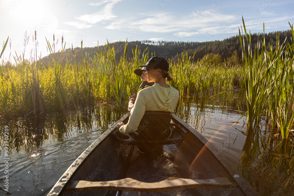 A mother holds her child in the front of a canoe on a lake. A mother holds her child in the front of a canoe on a lake.