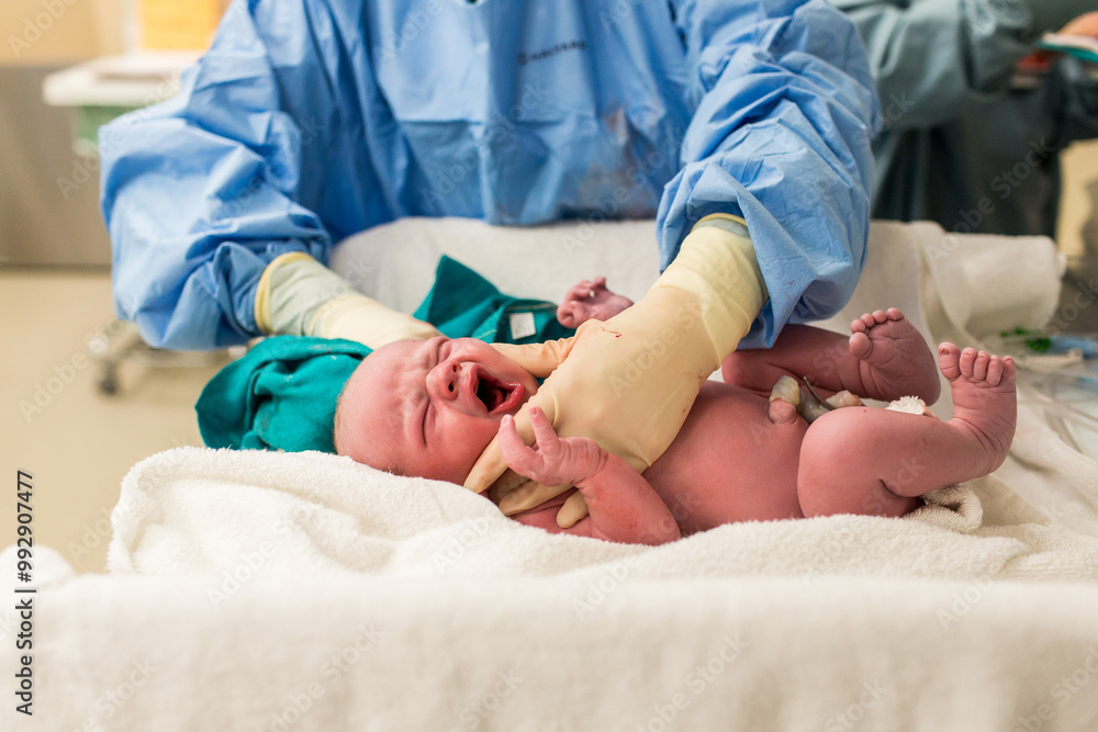 Newborn Baby Cries on Table Being Weighed in Hospital Room Newborn Baby Cries on Table Being Weighed in Hospital Room