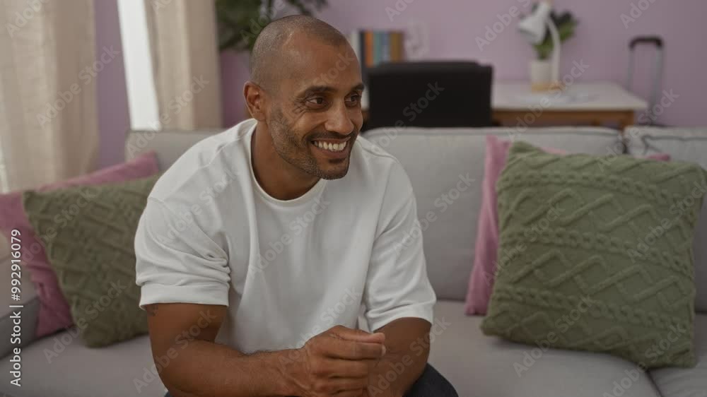 Young man smiling indoors sitting on a couch in a cozy living room Young man smiling indoors sitting on a couch in a cozy living room