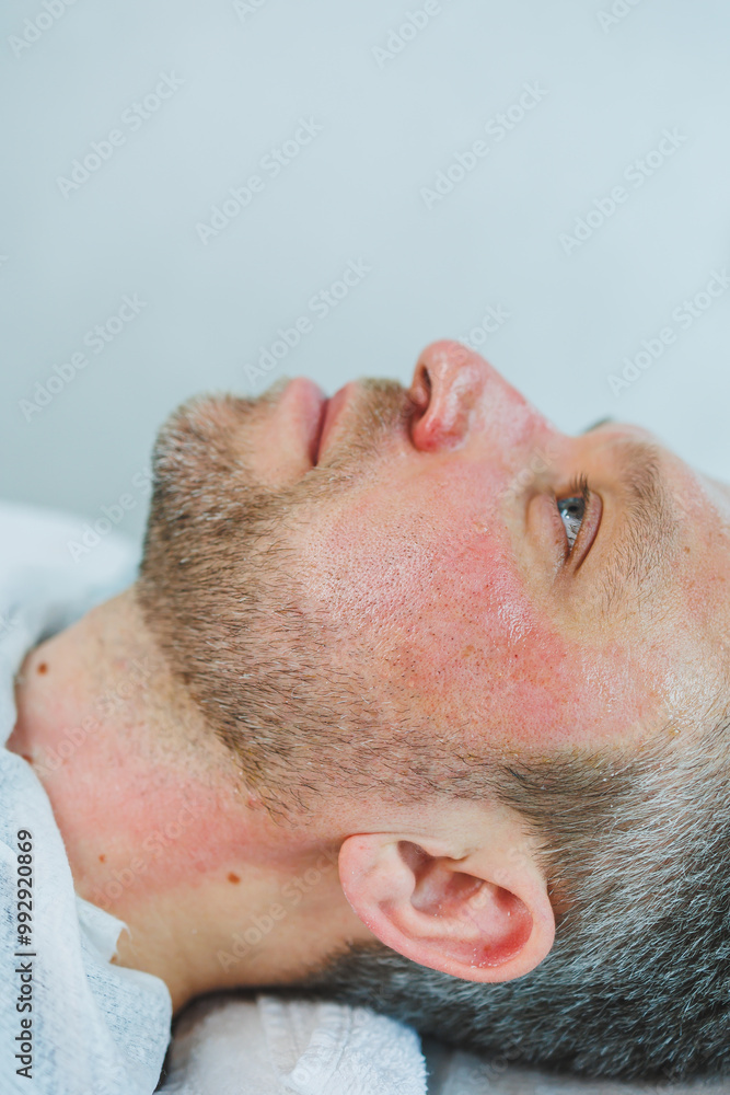 Naklejka premium Male cosmetology. A man lies at a cosmetologist for a facial treatment.