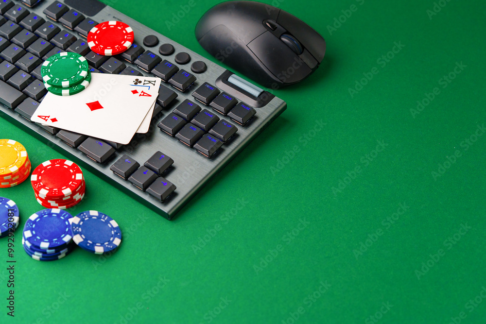 Chips and playing cards on a green felt surface near a computer keyboard Chips and playing cards on a green felt surface near a computer keyboard