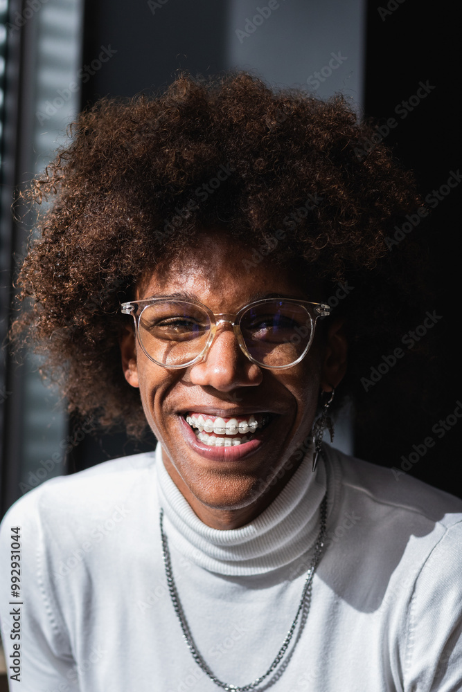 Cheerful young charismatic black male millennial with Afro hair in casual outfit and eyeglasses smiling and looking at camera Cheerful young charismatic black male millennial with Afro hair in casual outfit and eyeglasses smiling and looking at camera