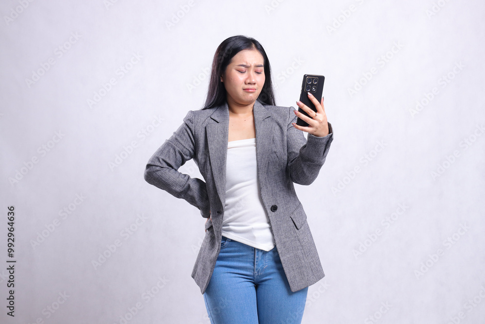 beautiful young office female sad down hold waist, holding cellphone wearing gray suit isolated on white background. for technology, lifestyle, shopping, transaction content beautiful young office female sad down hold waist, holding cellphone wearing gray suit isolated on white background. for technology, lifestyle, shopping, transaction content